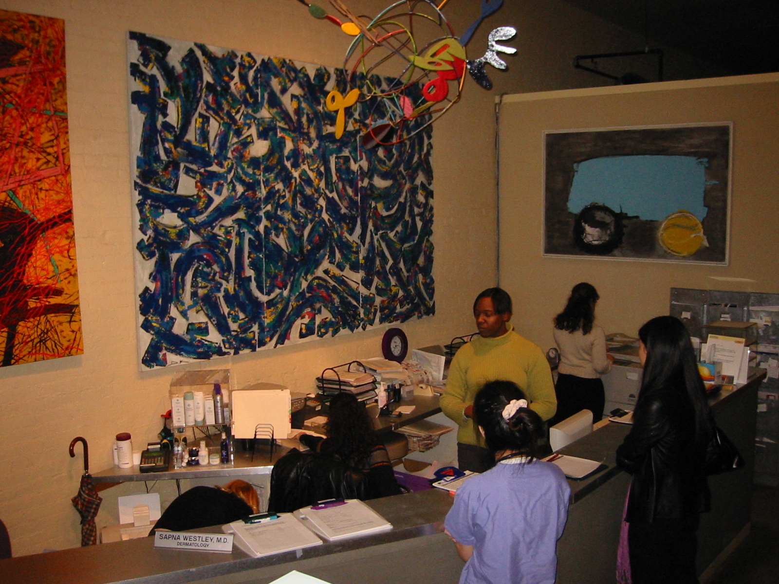 People gathered at the former reception desk beneath large paintings