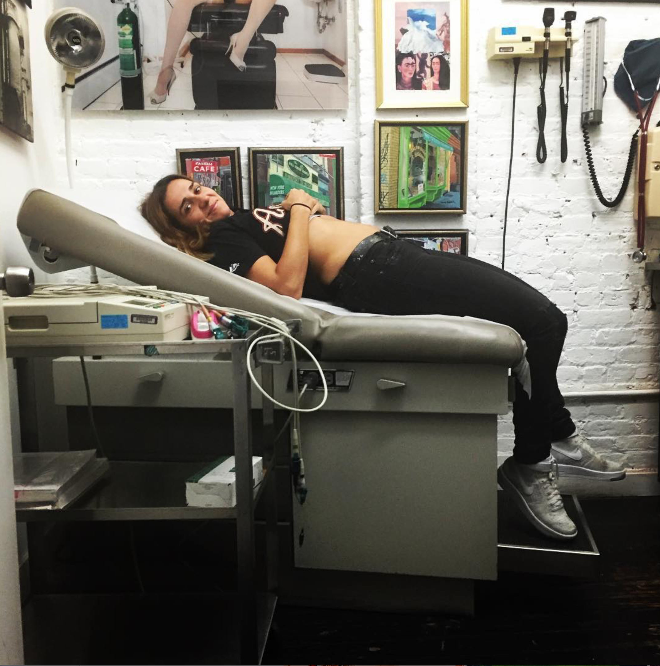 A visitor reclining on an exam table surrounded by artwork